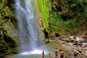 Some group of people sitting and bathing near waterfall