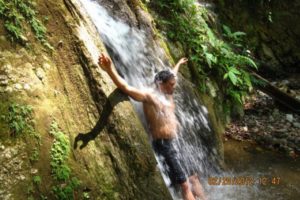 A boy taking bath at a waterfall in a jungle