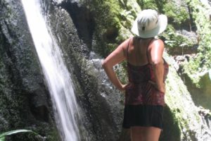 An old woman standing near a waterfall